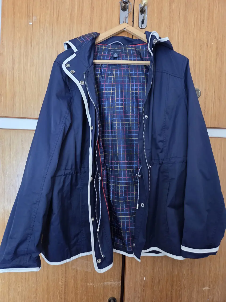 Campera impermeable azul marino con detalles blancos. Posee capucha, cierre y ajuste en la cintura. Ideal para días de lluvia.