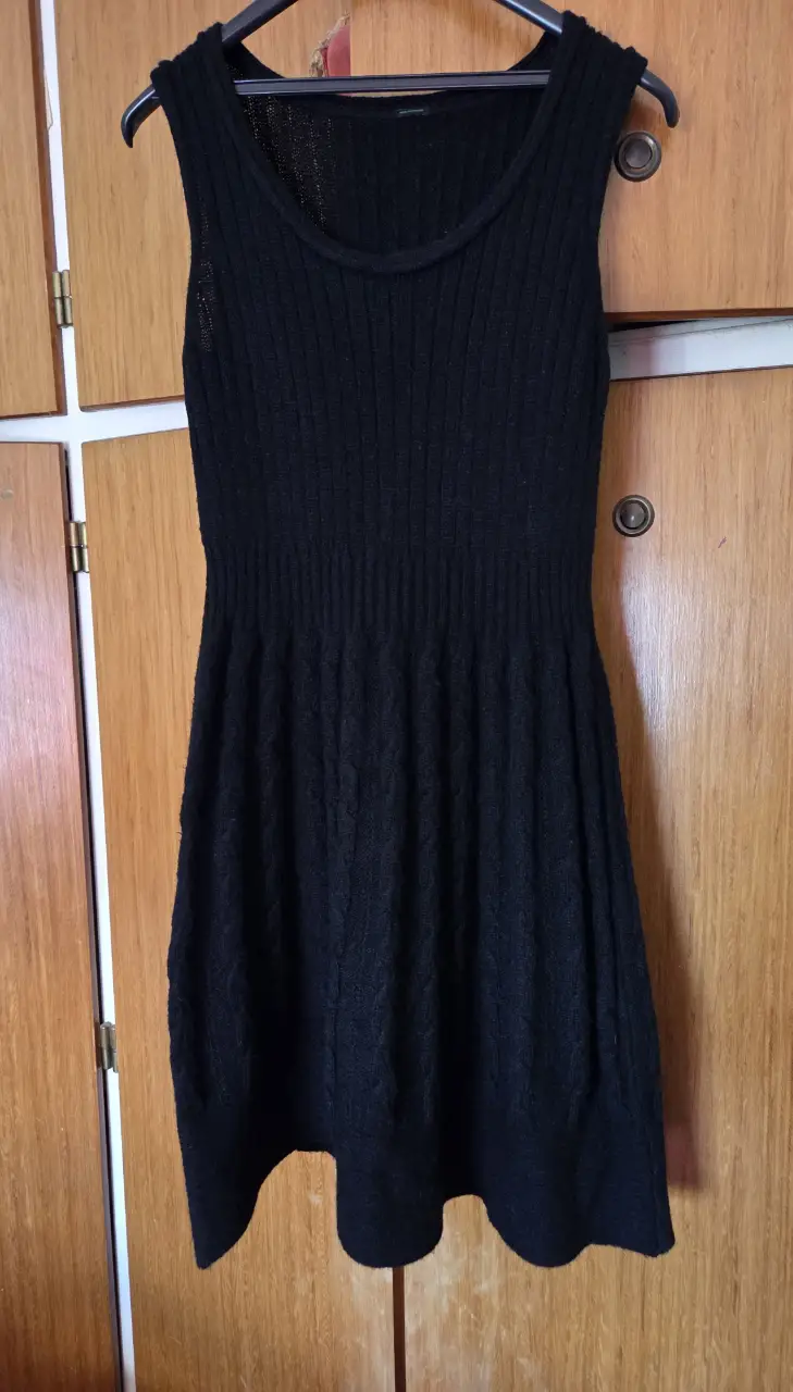 Vestido midi negro de punto, sin mangas, con diseño tejido y corte ajustado. Ideal para un look elegante y versátil.