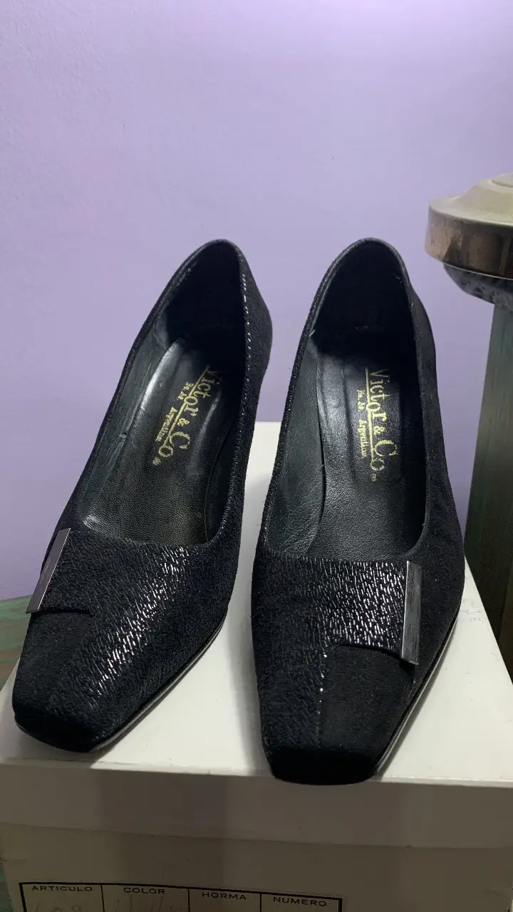 Elegantes zapatos de taco alto negros de la marca Victor & Co. con detalles metálicos en la puntera. Ideales para eventos formales o para darle un toque sofisticado a tu look. Gamuza combinada, se ve en las fotos. 