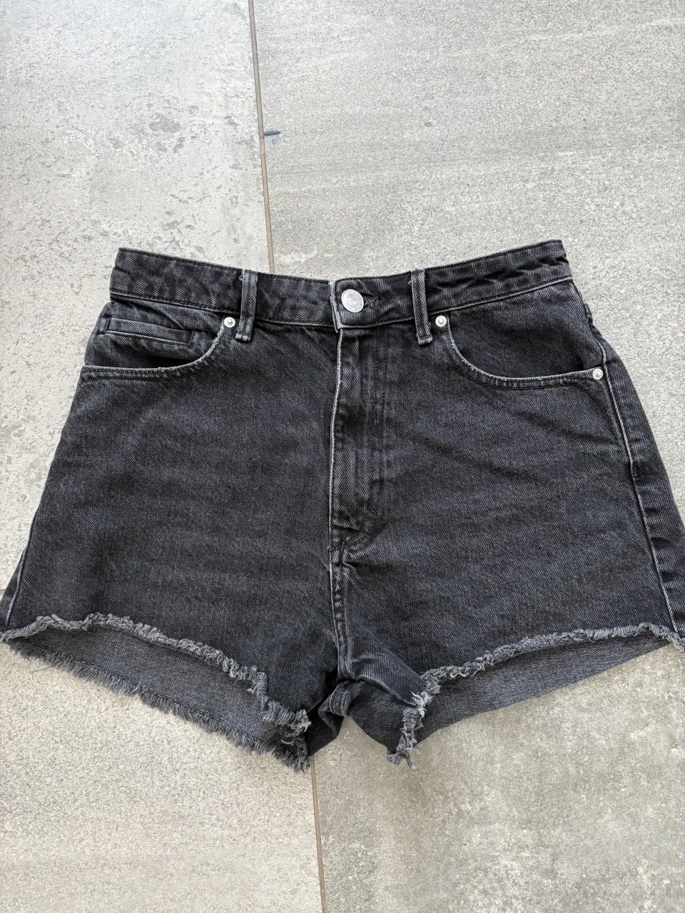 Shorts de jean negros con roturas y terminación desflecada en el ruedo.