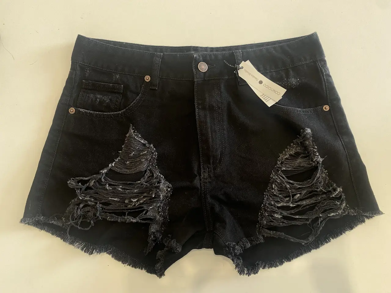 Short de jean negro con roturas en la parte delantera. Talle 30, tiro medio, ideal para un look casual y moderno. Marca Conocido Denim Studio.