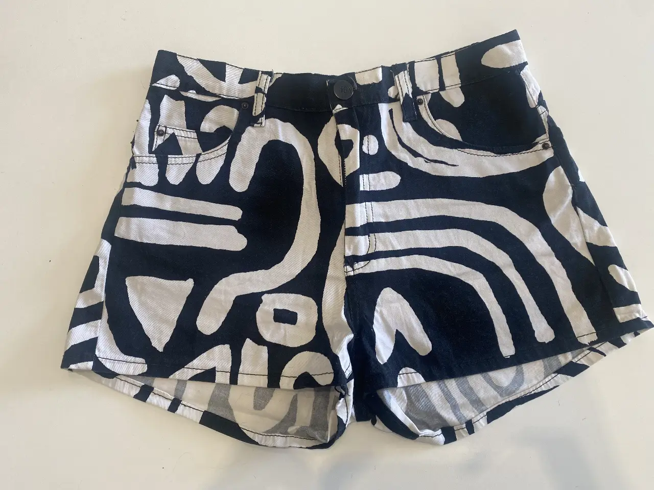 Short de jean con estampado abstracto en blanco y negro. Tiro medio, ideal para un look casual y moderno. Perfecto para el verano.