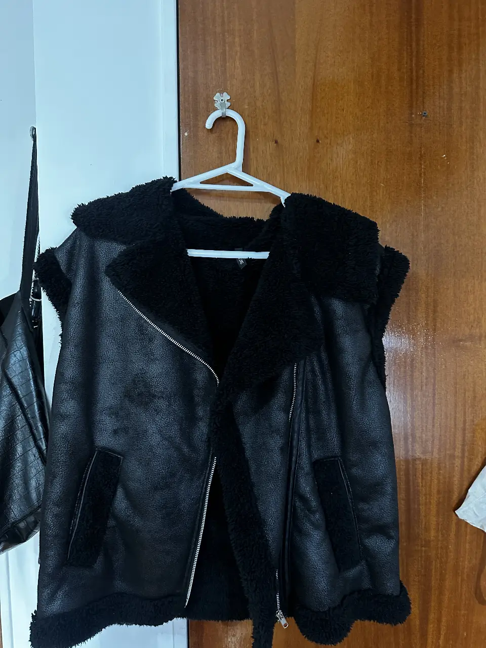Chaleco  negro con forro de piel sintética. Estilo gamulan, con cierre y bolsillos. Ideal para un look moderno y abrigado.