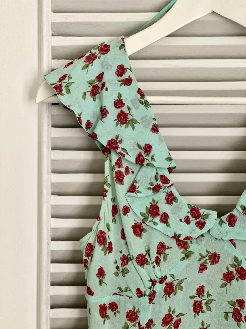 Vestido mini con estampado floral en tonos celeste y rojo. Diseño con volados en los hombros y escote en V. Ideal para un look fresco y romántico.