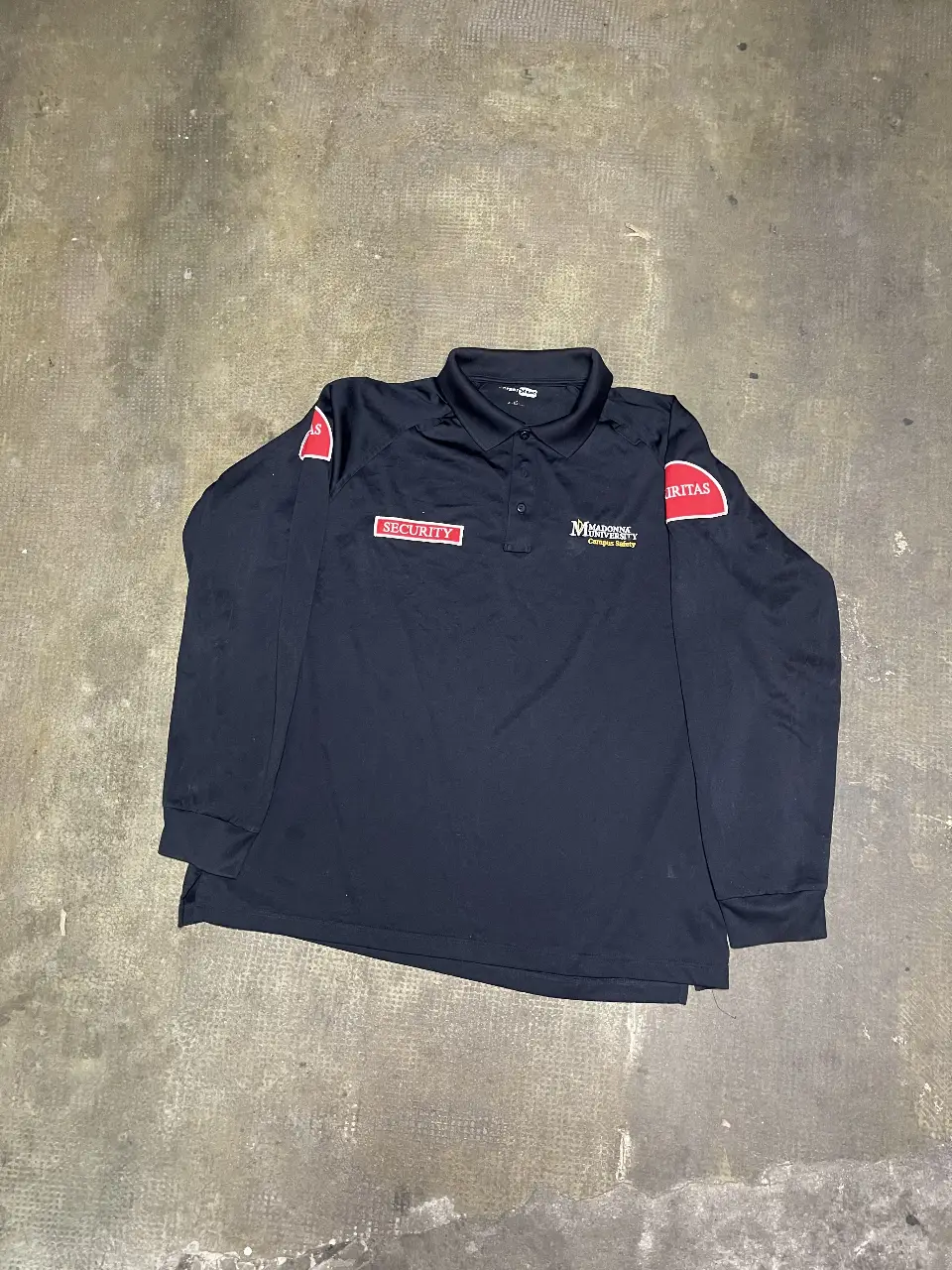 Remera de manga larga de seguridad de la Universidad Madonna, con logo y detalles en rojo y blanco. Ideal para trabajo o uso diario.