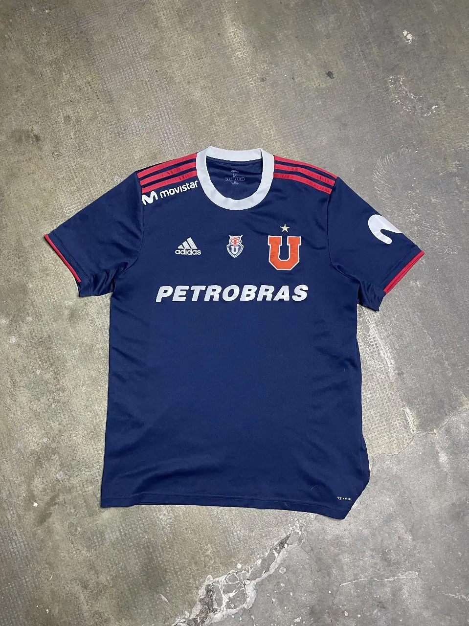 Camiseta de fútbol del equipo Universitario de Deportes, color azul marino con detalles en rojo y blanco. Con el logo de Adidas y el patrocinador Petrobras.