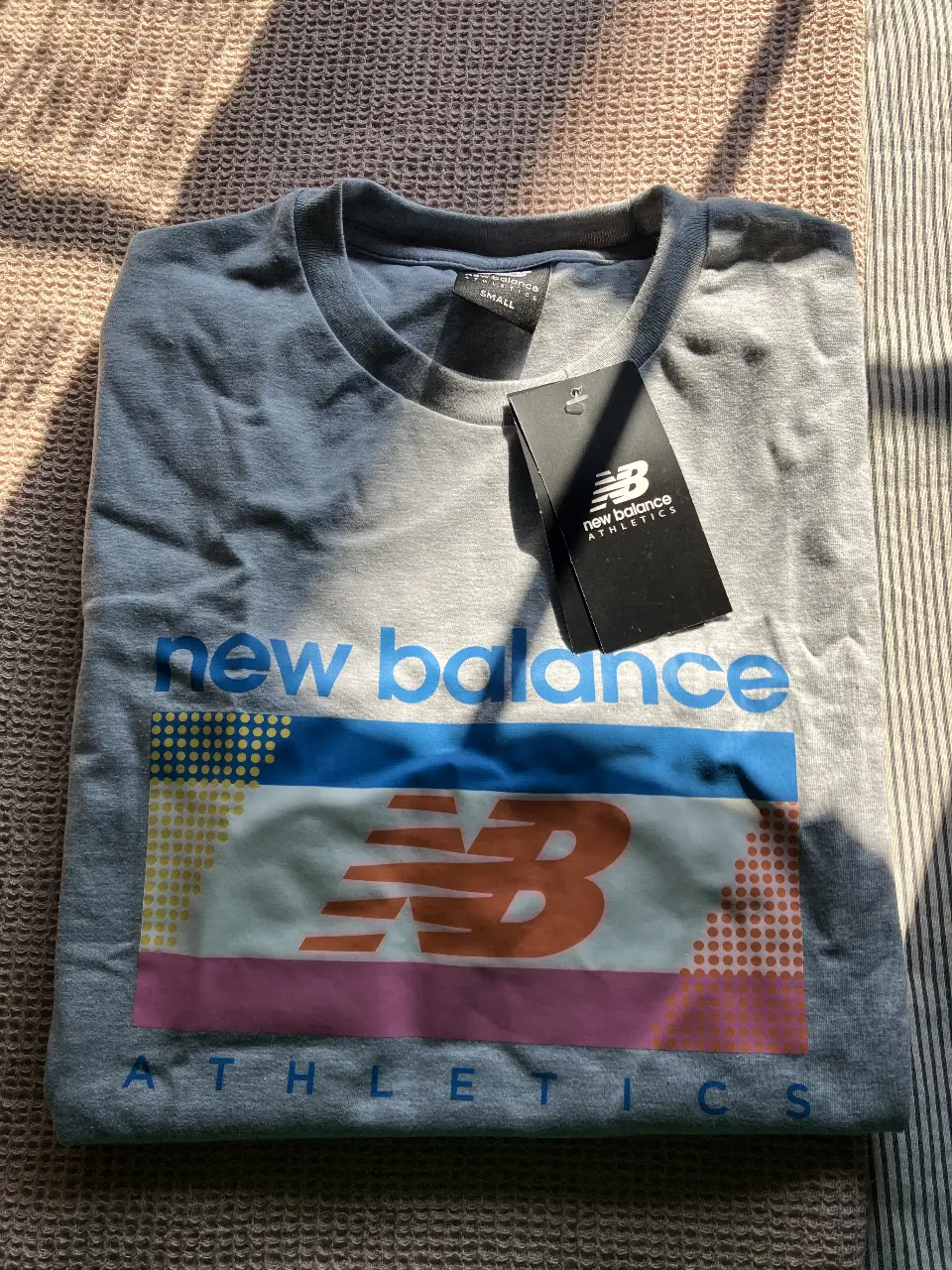 Remera New Balance de color gris con estampado en el frente. Ideal para actividades deportivas o uso casual.