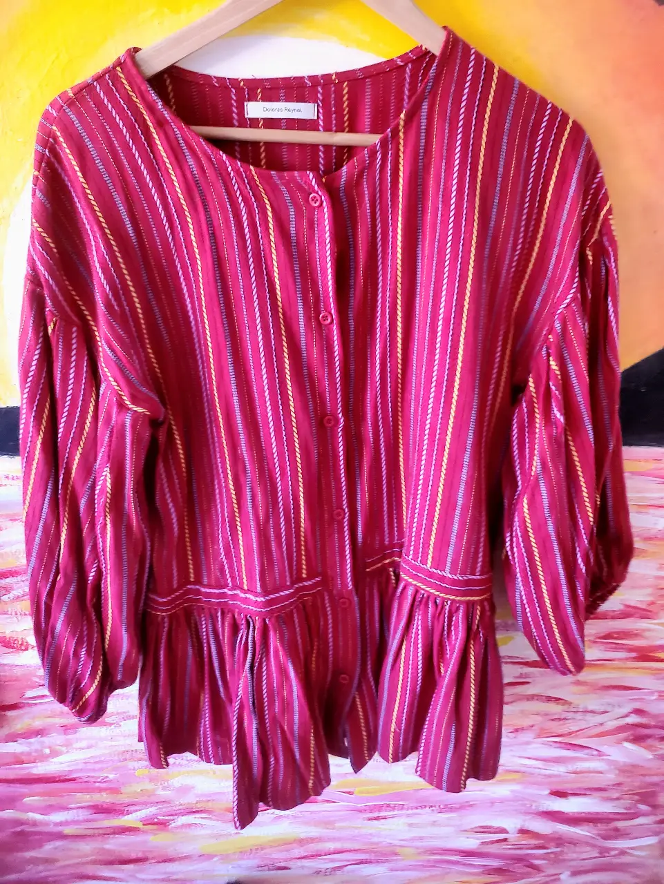 Blusa a rayas roja con detalles en amarillo y blanco. Diseño con volados en la cintura y mangas amplias. Ideal para un look casual y con estilo.