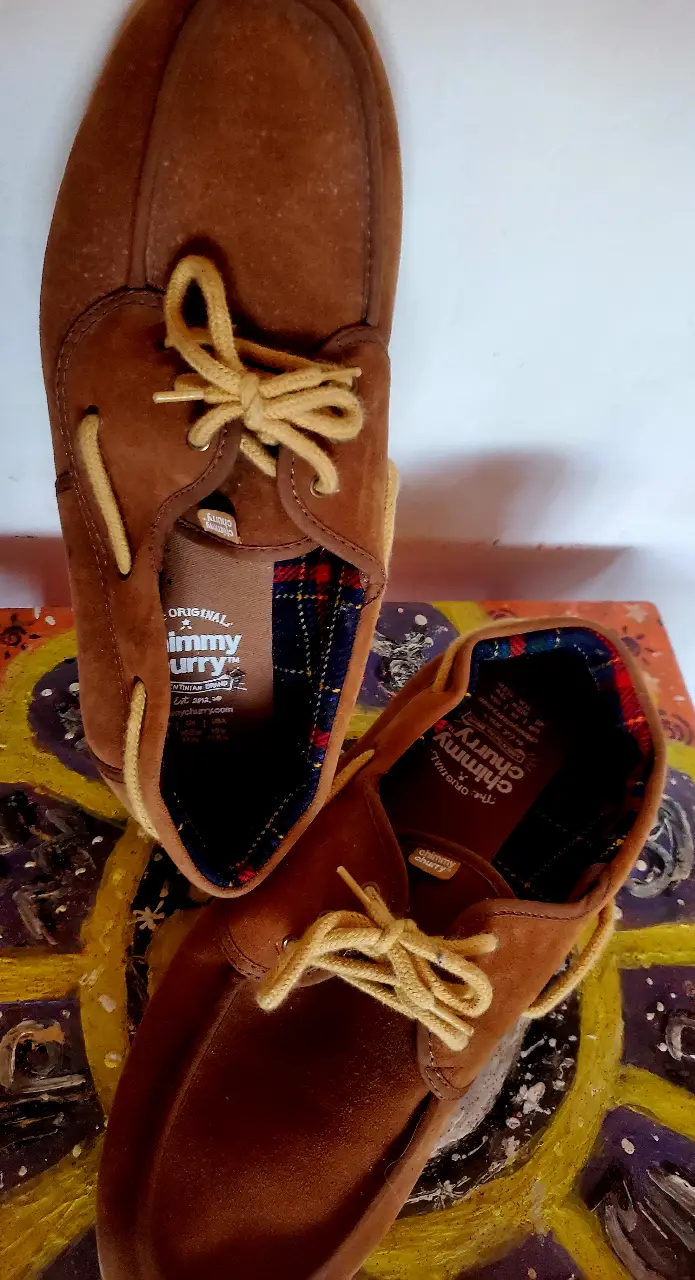 Mocasines Chimmy Cherry originales de gamuza marrón, con cordones amarillos y detalles a cuadros en el interior. Un clásico para un look casual y cómodo.