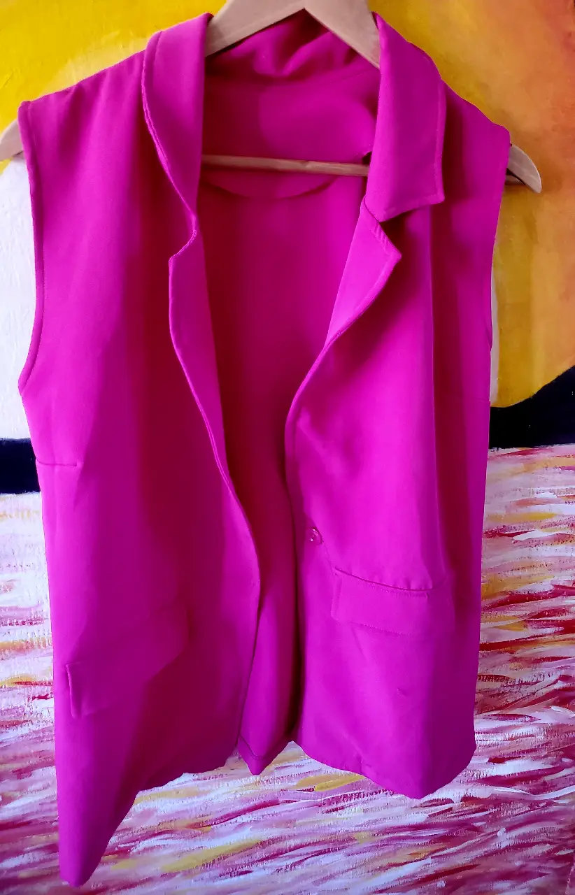 Chaleco sastrero fucsia sin mangas, con solapas y un botón. Ideal para un look moderno y elegante.