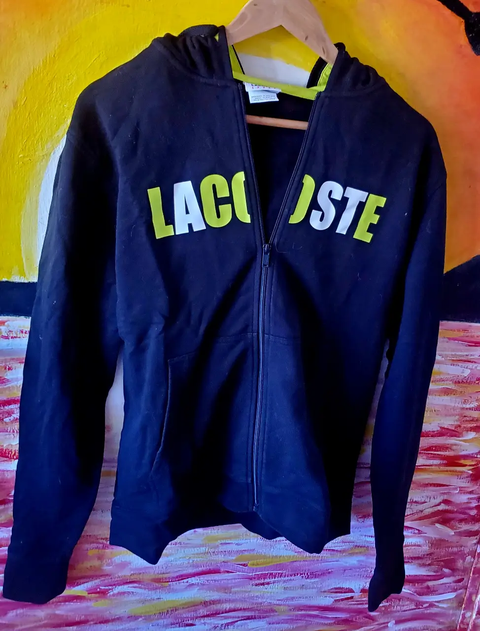 Buzo con cierre Lacoste negro con logo en amarillo. Ideal para un look deportivo y casual.