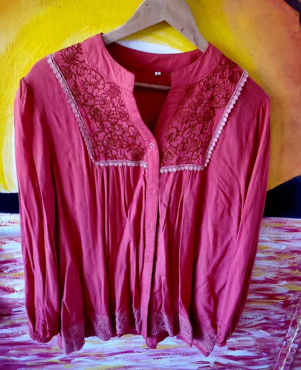 Blusa roja con bordados en el cuello y mangas largas. Ideal para un look elegante y femenino.