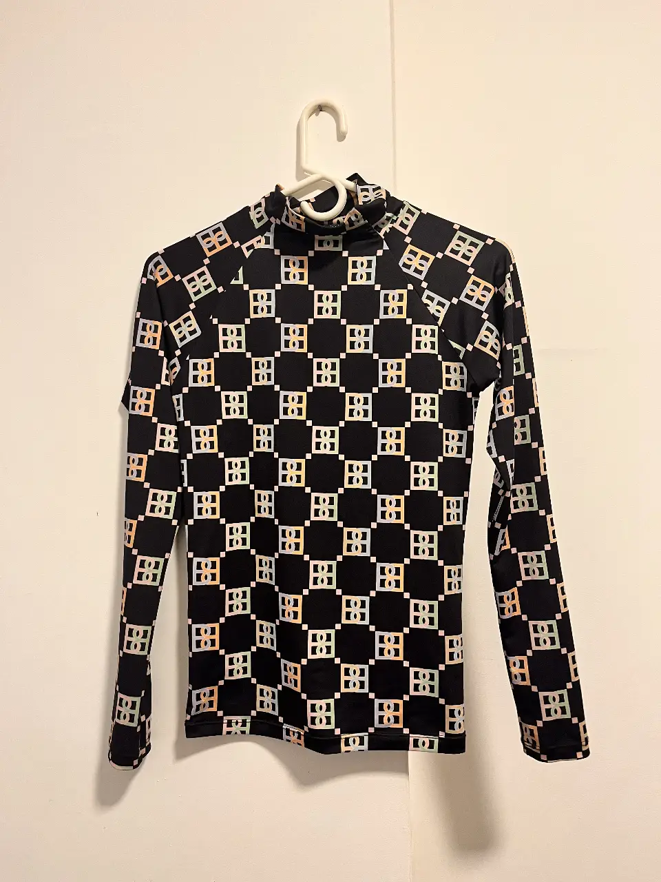 POLERA FANCY con cuello alto y estampado geométrico en tonos pastel y negro. Ideal para un look moderno y llamativo.