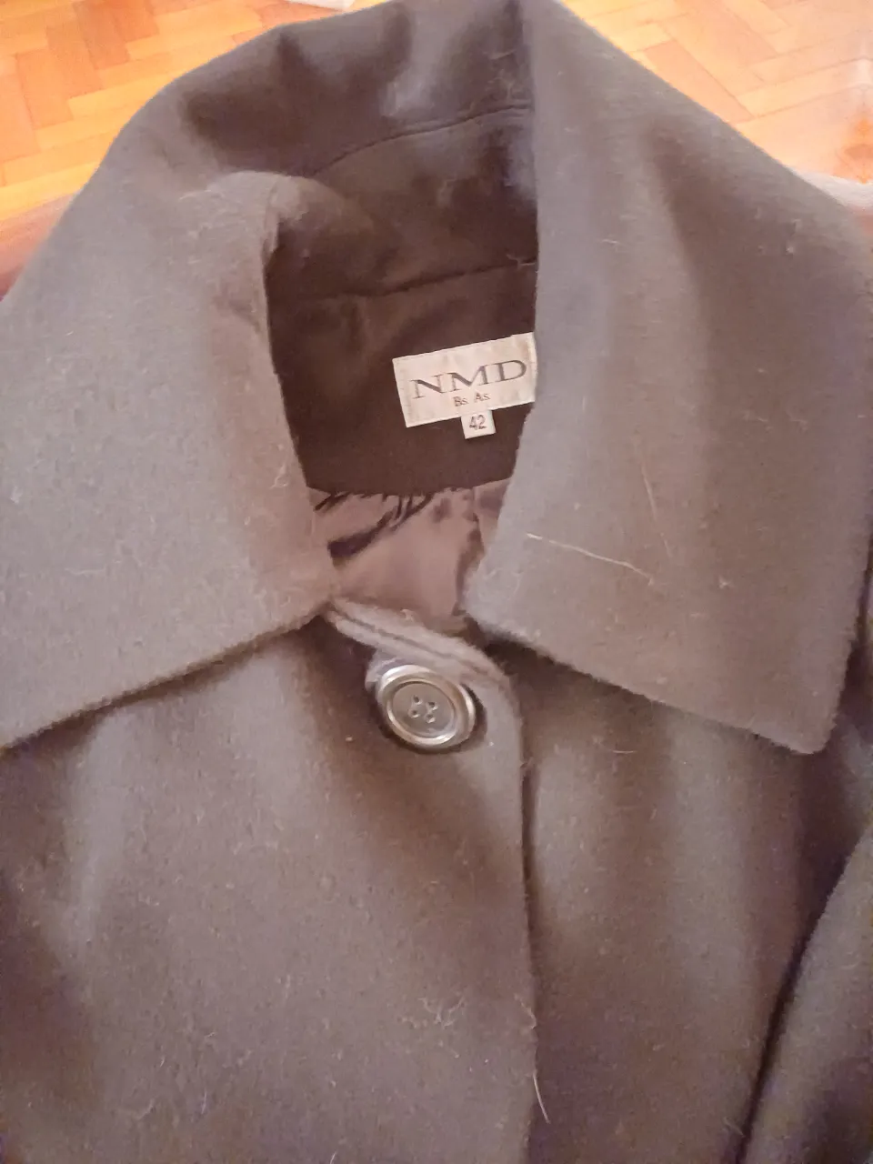 Tapado de paño color marrón oscuro, con cuello grande y botón. Ideal para el invierno. Talle 42. Es corto, tipo trapecio y mangas al codo.