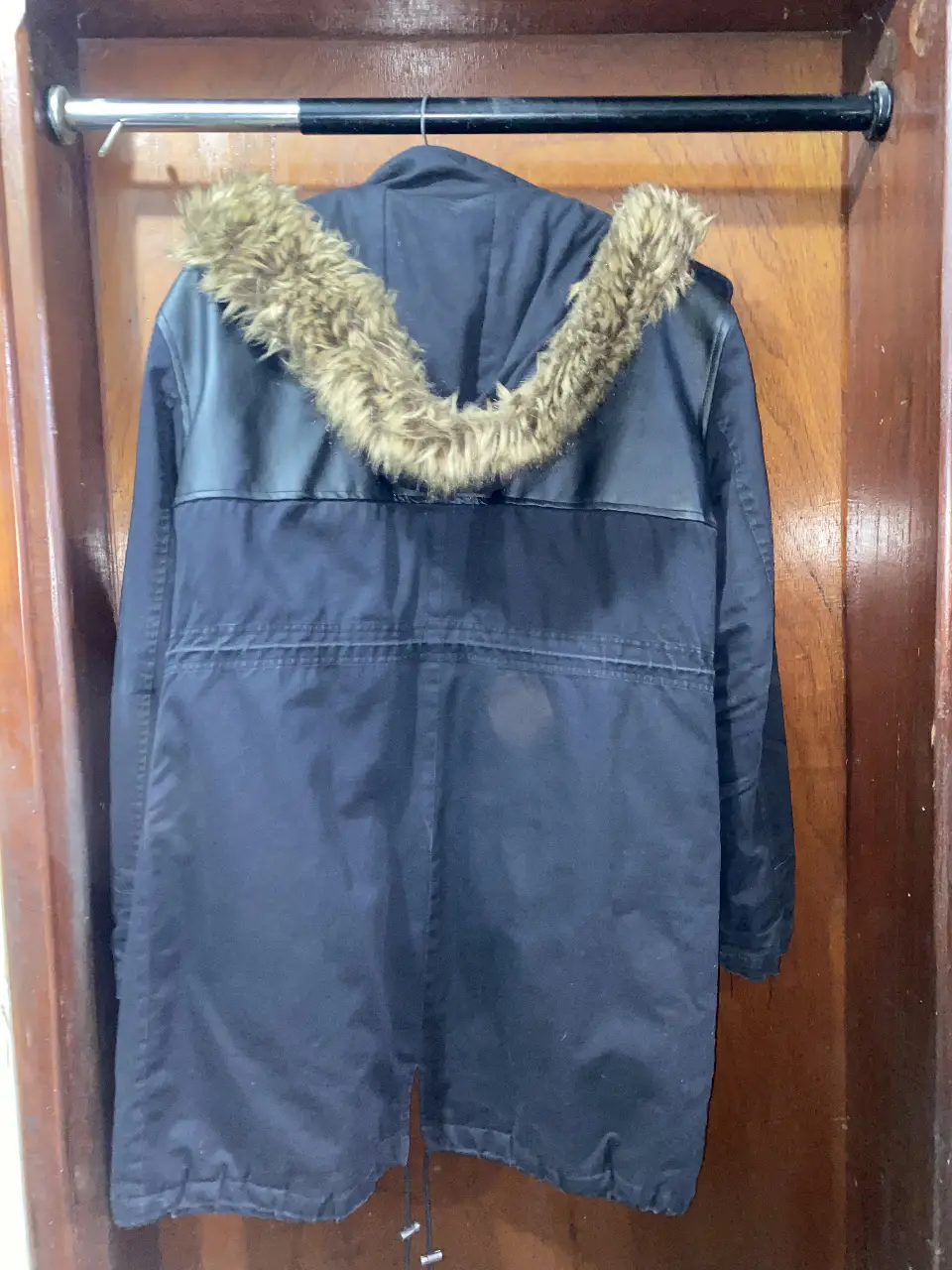 Campera de abrigo para mujer, color negro con detalles en marrón. Posee capucha con borde de piel sintética, ideal para el invierno. Perfecta para un look casual y abrigado.