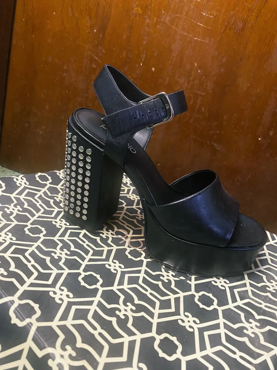 Sandalias de taco alto negras con plataforma y detalles de tachas en el taco. Marca Paruolo.