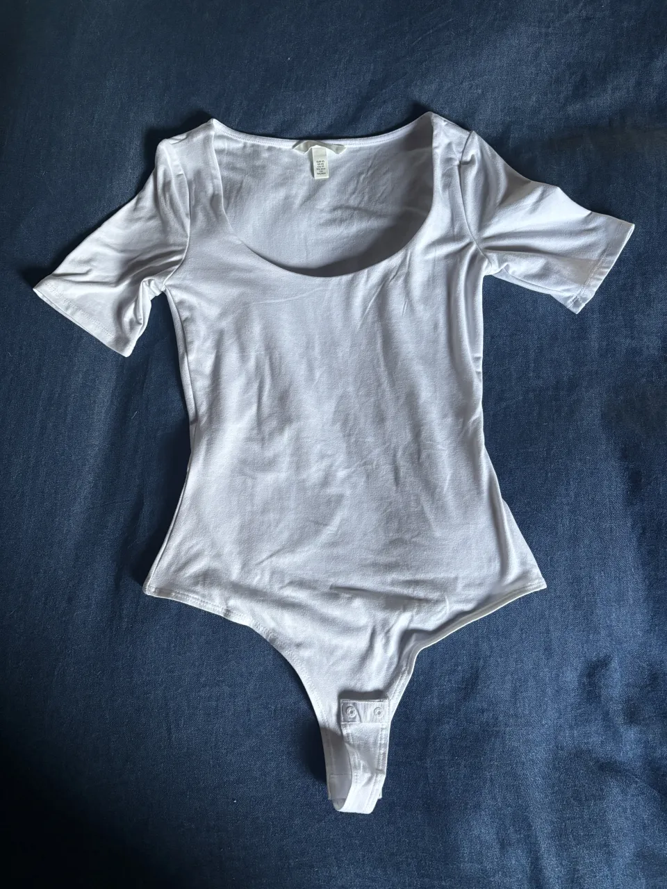 Body blanco de manga corta con escote cuadrado y broches inferiores.