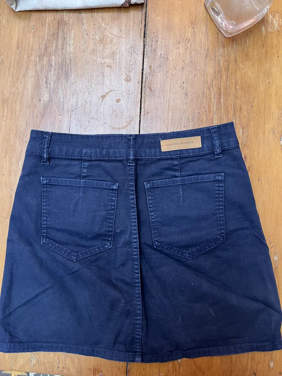 Pollera de jean azul marino de la marca Cuesta Blanca, talle 42. Con botones frontales y bolsillos traseros.