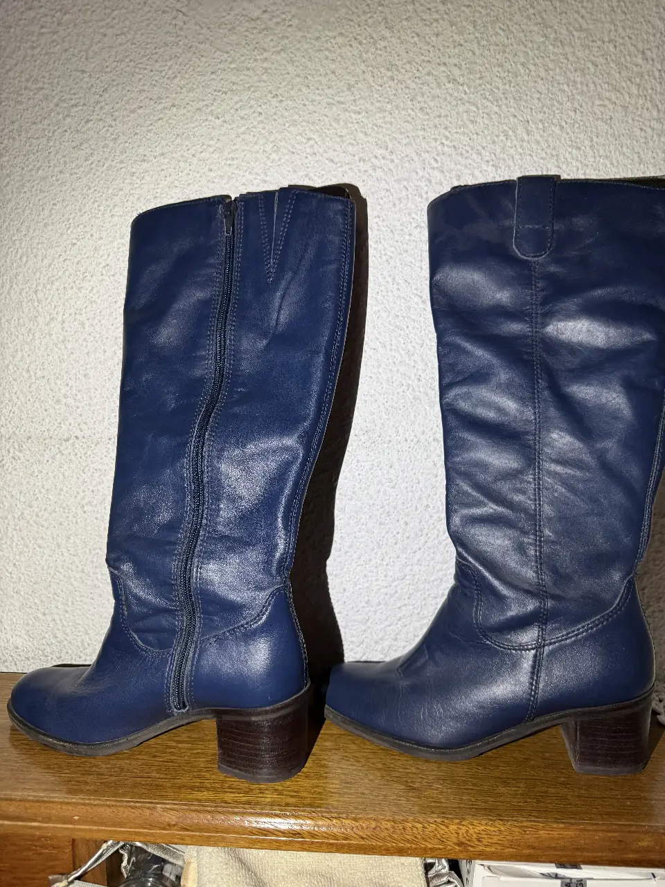 Botas de caña alta de cuero azul marino, con cierre lateral y taco bajo. Ideales para un look elegante y moderno.