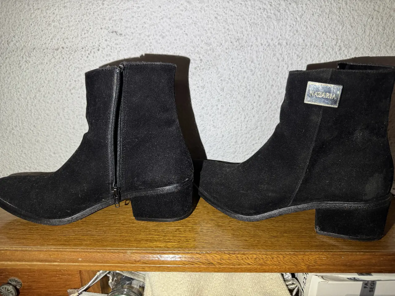 Botines de gamuza negros con cierre lateral y detalle metálico con la marca Nazaria. Ideales para un look casual y moderno.