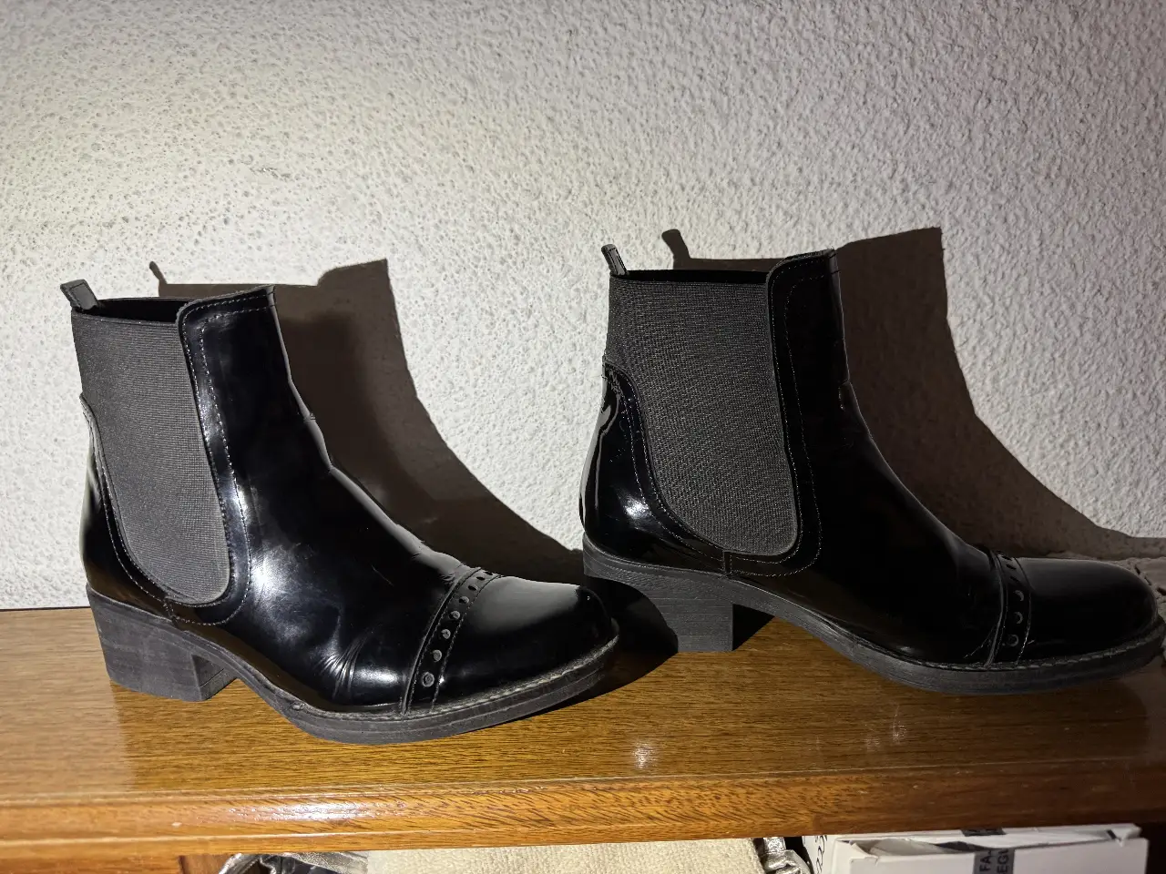 Botines negros de charol con detalles en la puntera. Ideales para un look elegante y moderno.