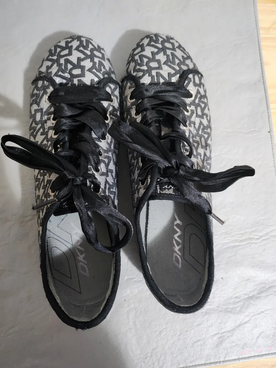 Zapatillas DKNY con estampado del logo en blanco y negro. Cordones negros. Suela de goma negra.