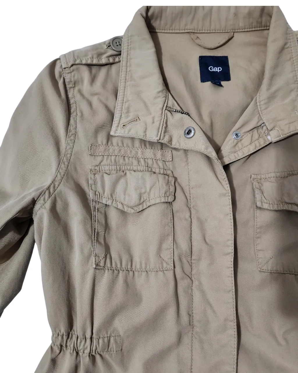 Campera Gap estilo militar en color khaki. Posee múltiples bolsillos, ajuste en la cintura y detalles en los hombros. Ideal para un look casual y versátil.