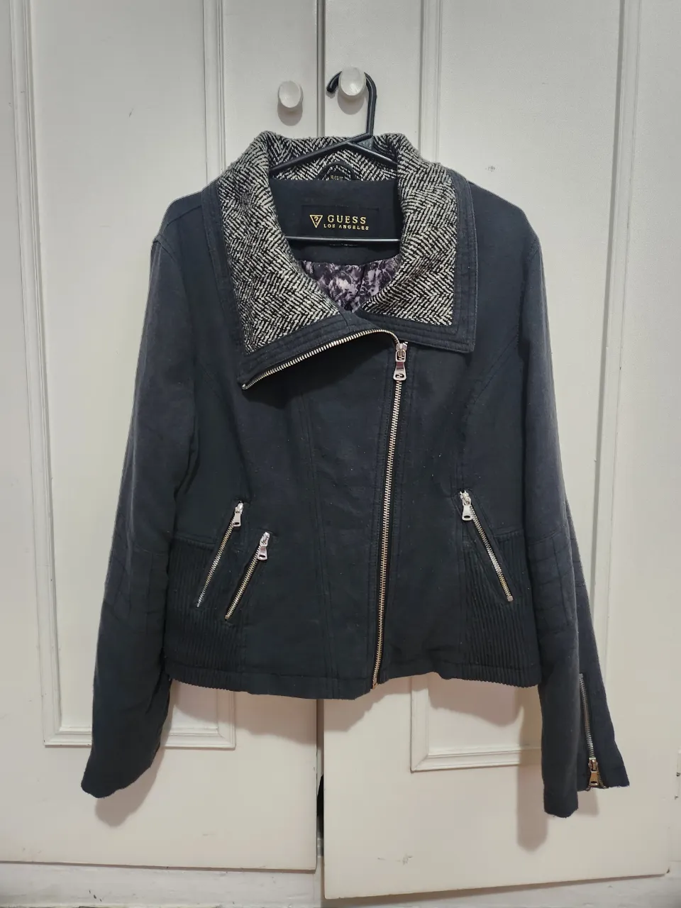 Campera biker de mujer, color negro, con cuello solapa y cierre asimétrico. Detalles de cremalleras en bolsillos y mangas. Diseño entallado y moderno, ideal para un look urbano y con estilo.