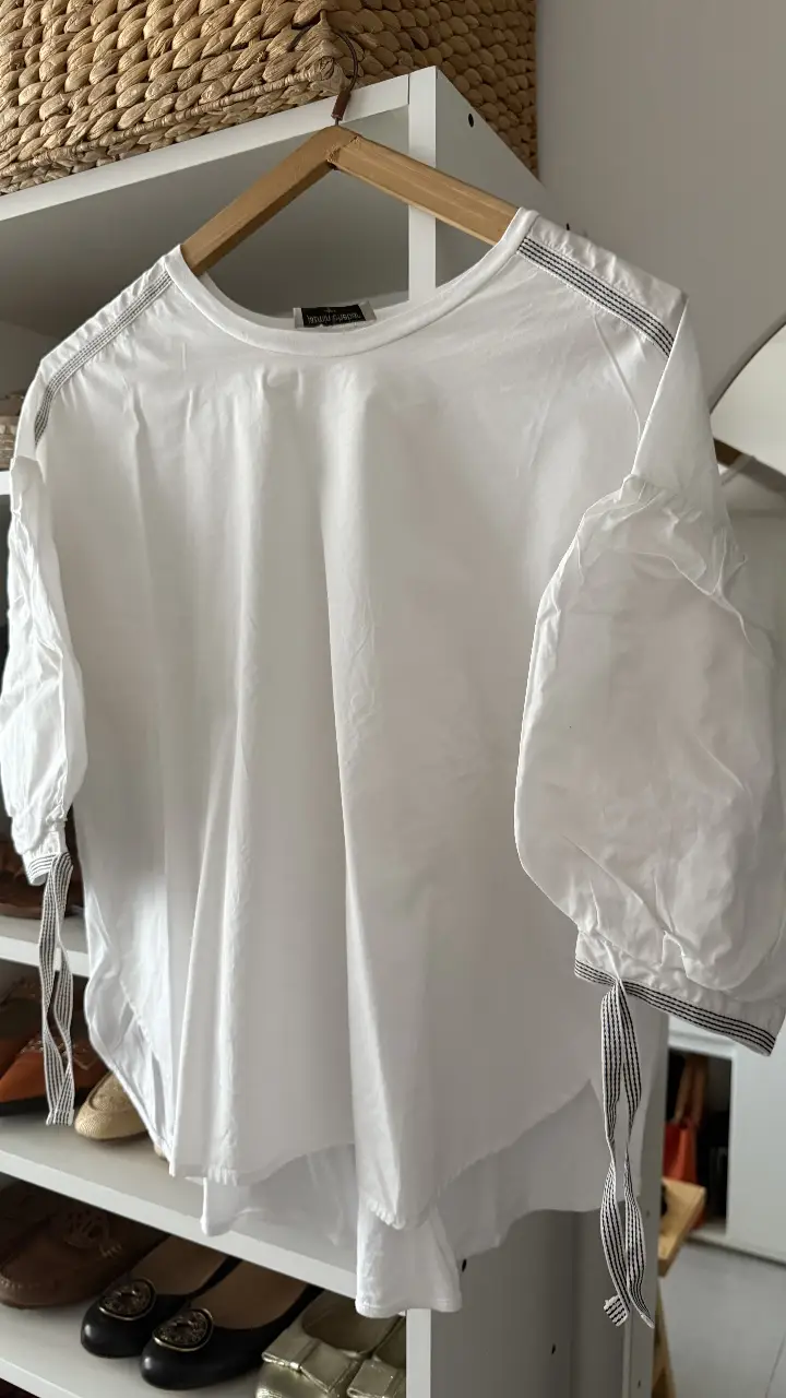 Blusa blanca de jazmin chebar, con mangas 3/4 abullonadas y detalles en negro. Ideal para un look casual y elegante.