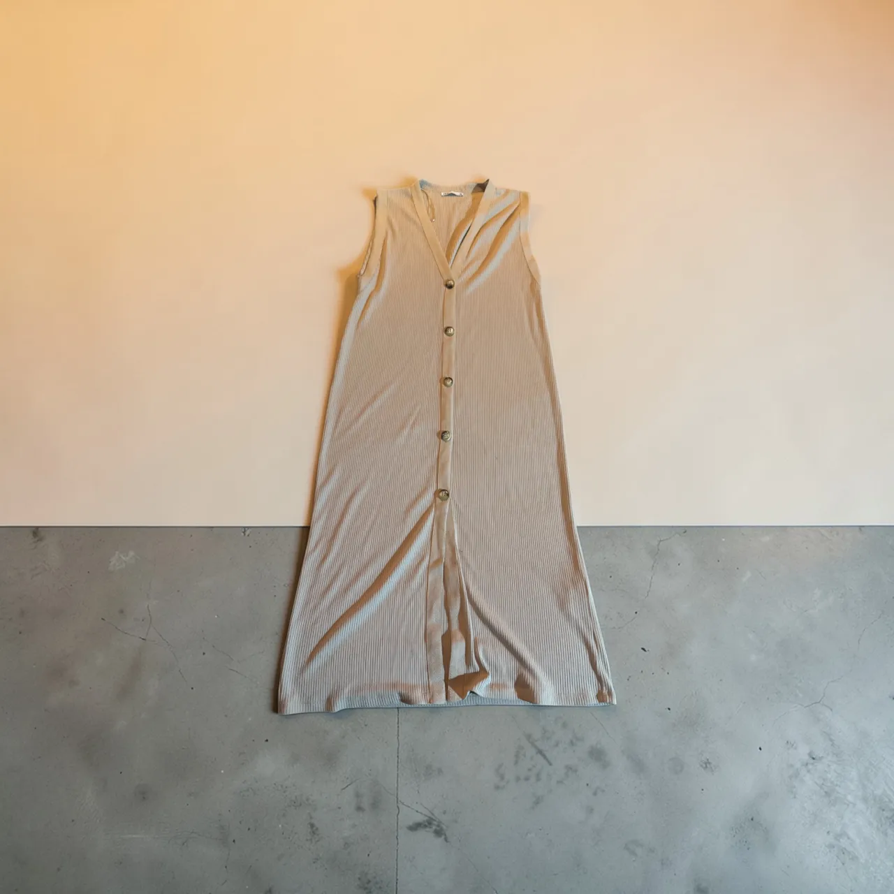 Vestido largo de tejido acanalado, sin mangas y con cuello en V. Posee botones al frente y una abertura lateral. Ideal para un look casual de verano.