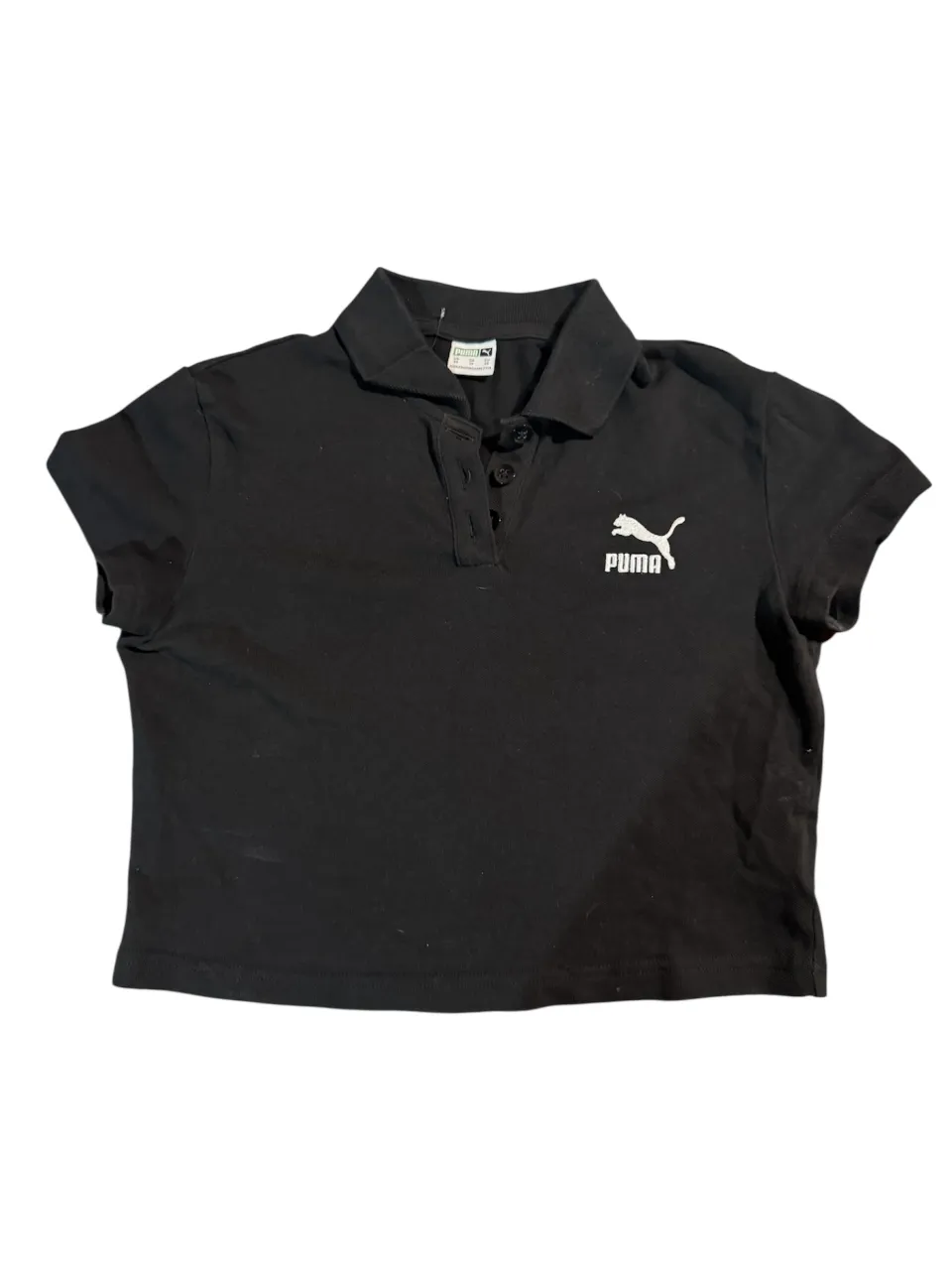 chomba negra corta de Puma, manga corta y corte crop. Ideal para un look casual y deportivo.