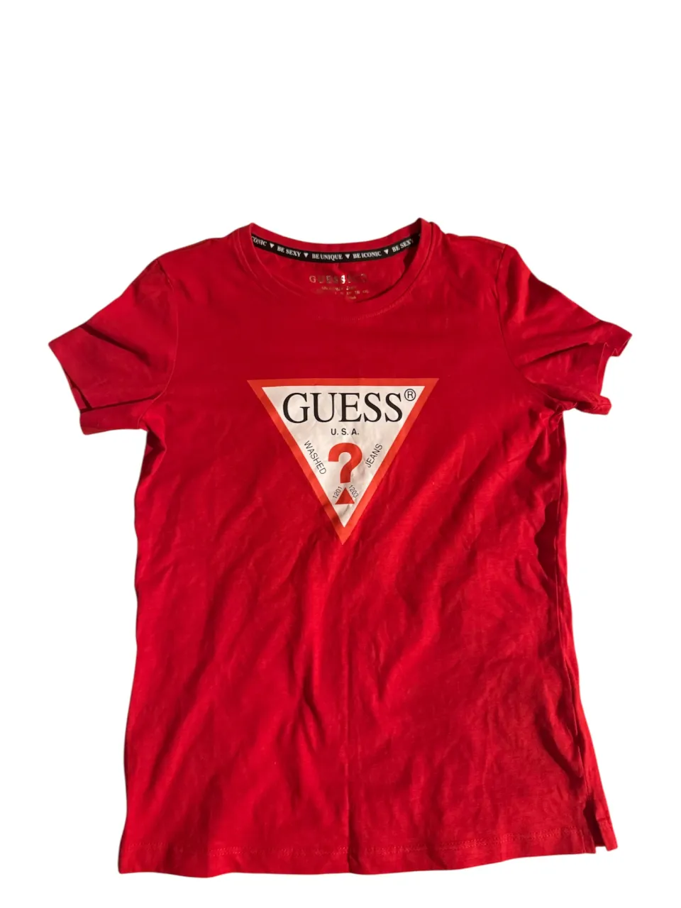 Remera roja de manga corta con el icónico logo de Guess en el frente. Un clásico que no puede faltar en tu guardarropa.