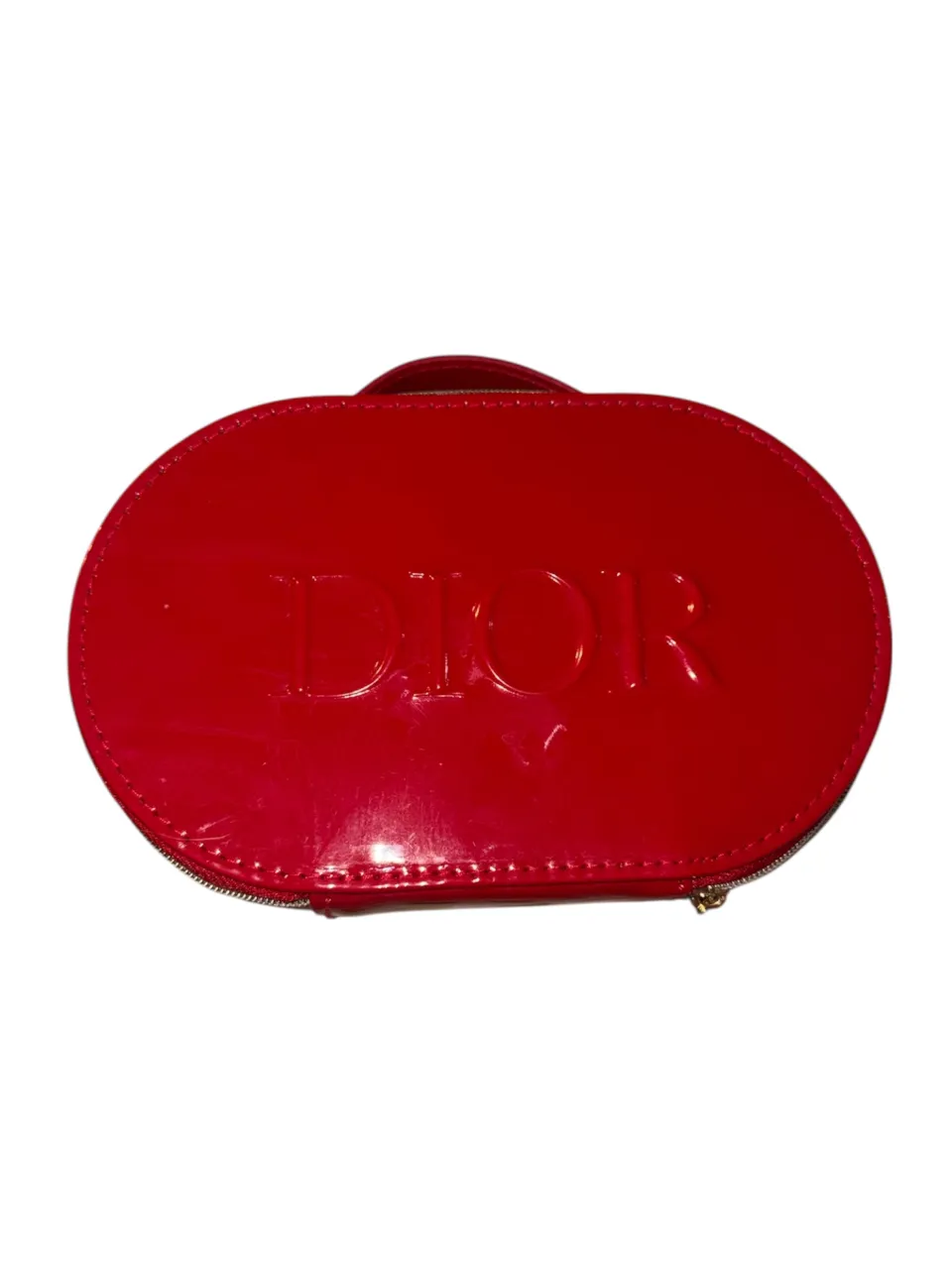 Neceser Dior rojo brillante, ideal para llevar tus esenciales de maquillaje o como un accesorio chic. Su diseño ovalado y el logo en relieve le dan un toque de lujo.