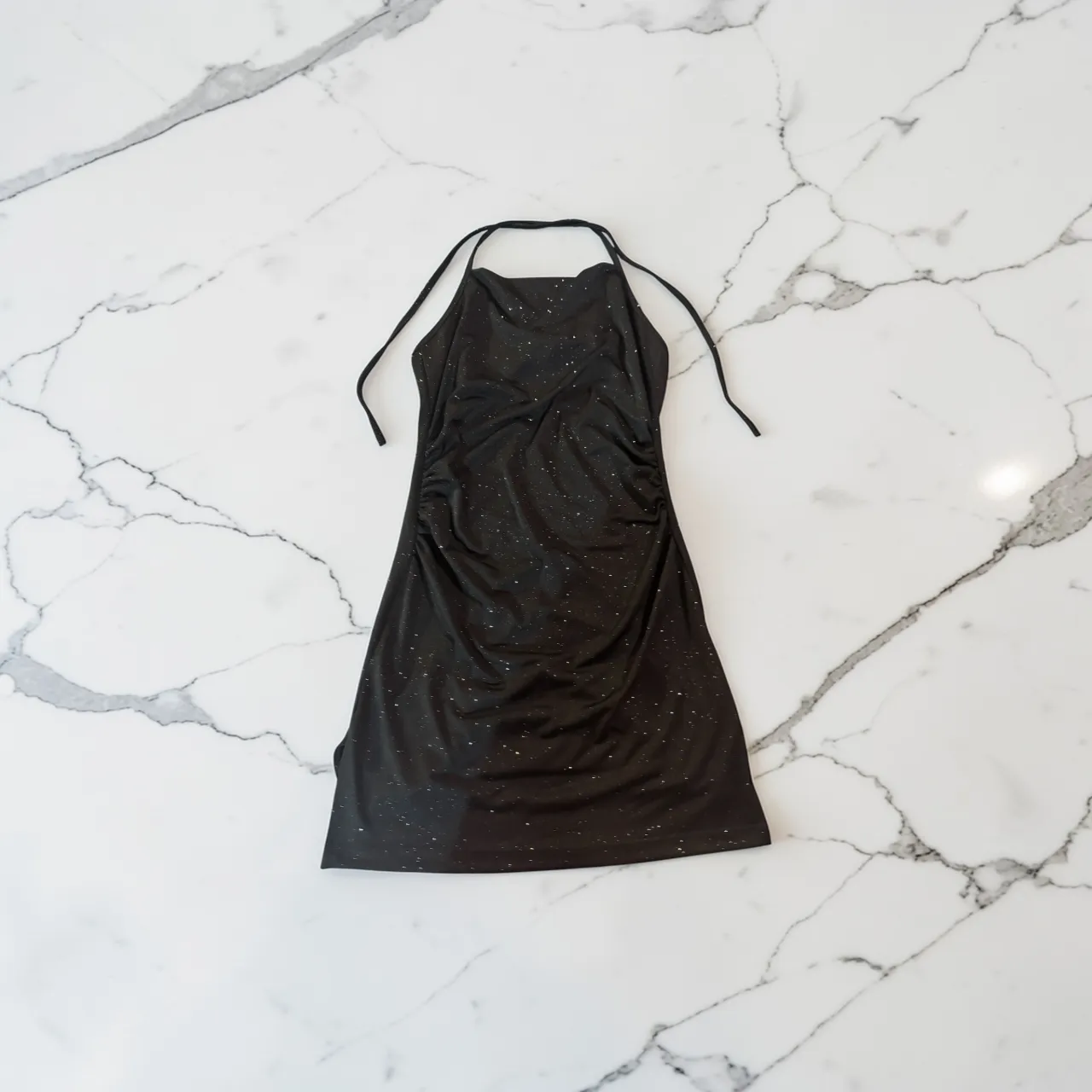 Vestido negro con brillos, escote halter y detalles fruncidos. Ideal para fiestas o salidas nocturnas.