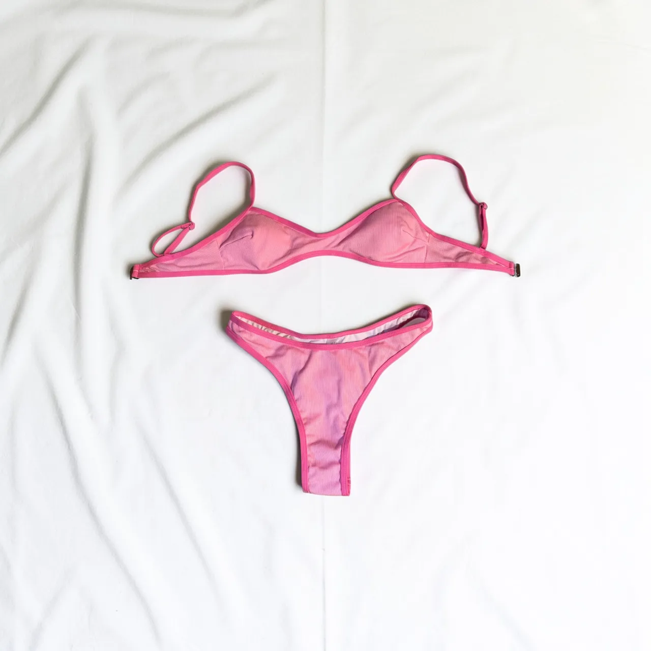 Conjunto de bikini rosa a rayas blancas, con corpiño triangular y bombacha colaless. Ideal para disfrutar del sol y el mar.