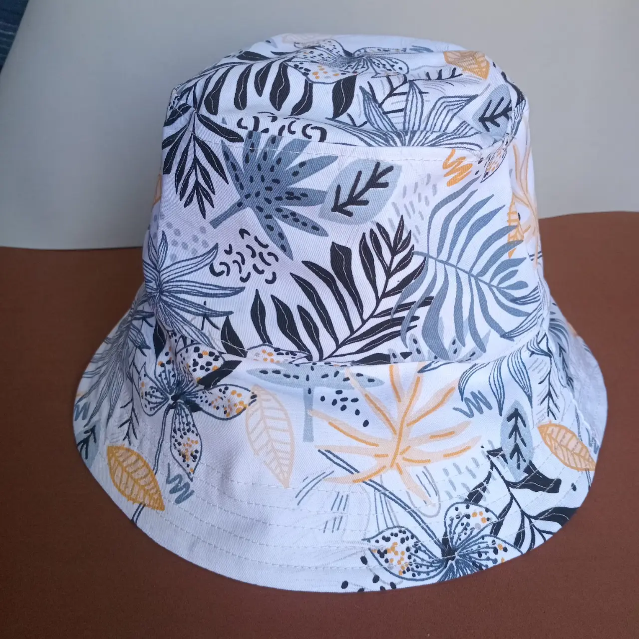 Sombrero bucket con estampado floral en tonos blanco, gris y amarillo. Ideal para un look casual y fresco.