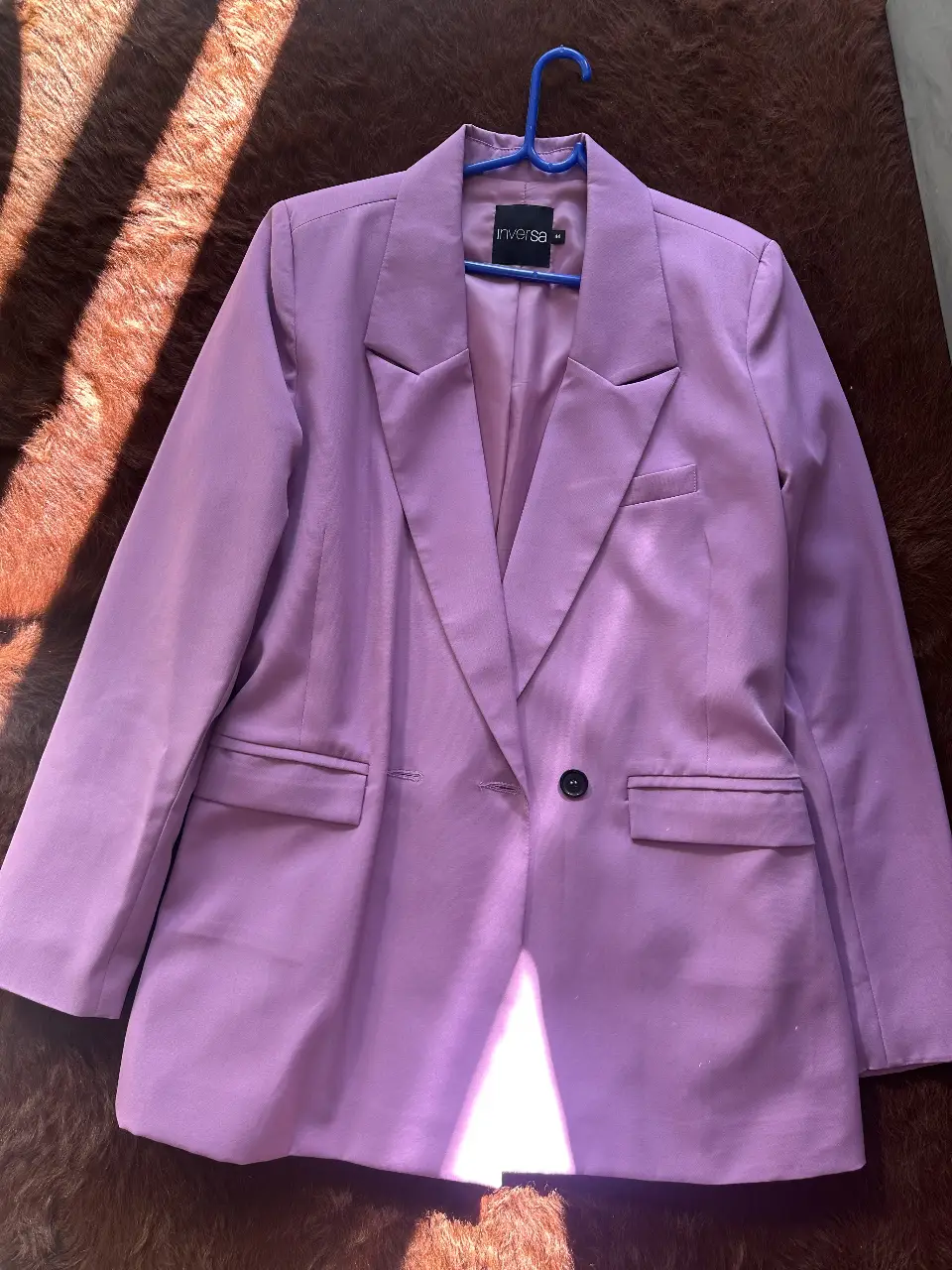 Elegante blazer de mujer en un vibrante tono lila. Confeccionado para un look sofisticado, ideal para eventos formales o para darle un toque de color a tu outfit de trabajo. Diseño clásico con solapas y un solo botón.