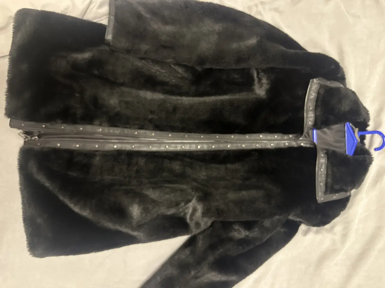 Campera de piel sintética negra, con detalles de cuero y tachas en el cuello y cierre. Ideal para un look moderno y abrigado.