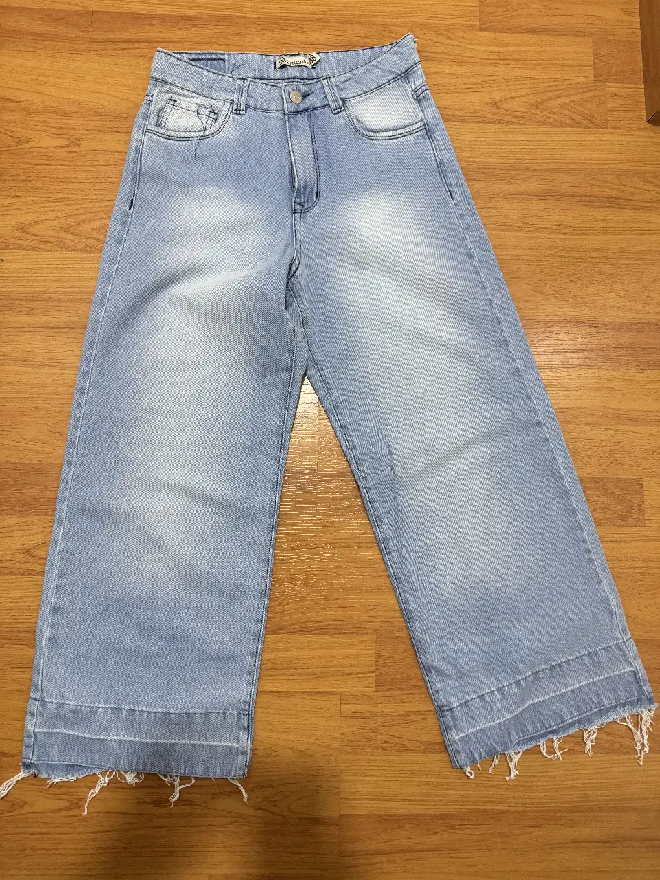 Jeans rectos de mujer, tiro medio, color azul claro, con detalles de desgaste en la tela y terminación desflecada en el bajo. Un clásico para cualquier ocasión.