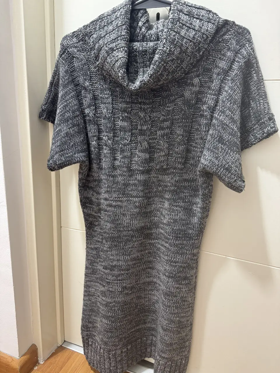 Sweater largo de mujer, tejido en punto grueso con cuello alto y mangas cortas. Ideal para un look casual y abrigado en invierno.