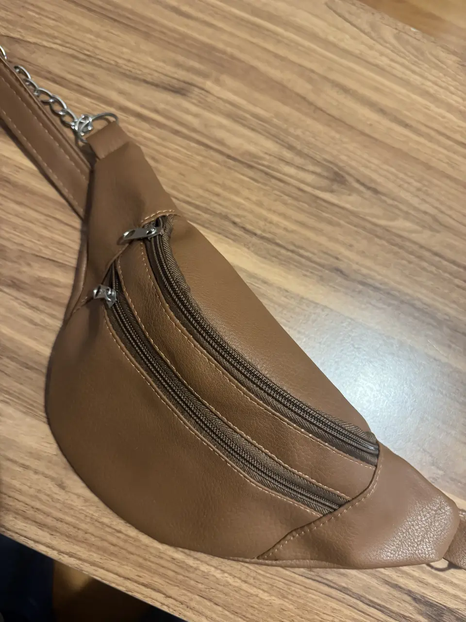 Riñonera de cuero sintético marrón con múltiples compartimentos y cierre. Ideal para llevar tus esenciales con estilo y comodidad.