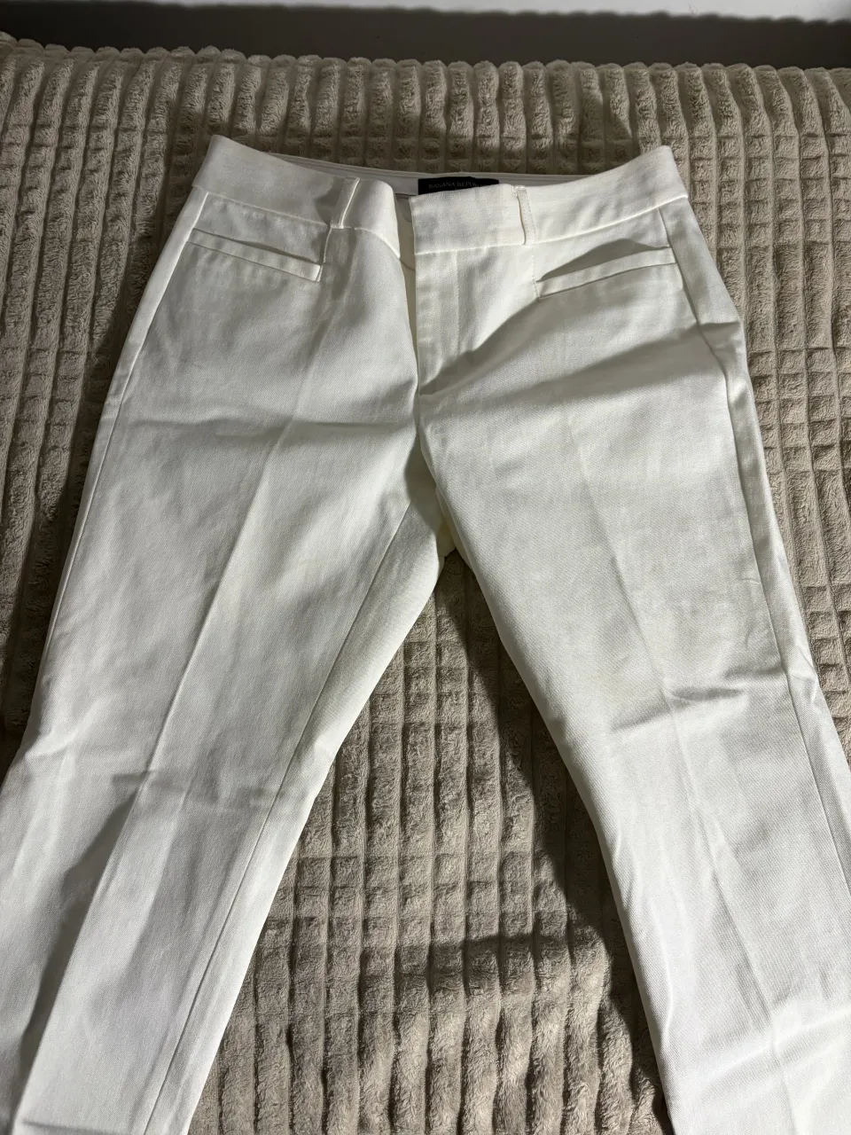 Pantalón blanco de vestir, corte recto y tiro medio. Ideal para un look elegante y profesional. 