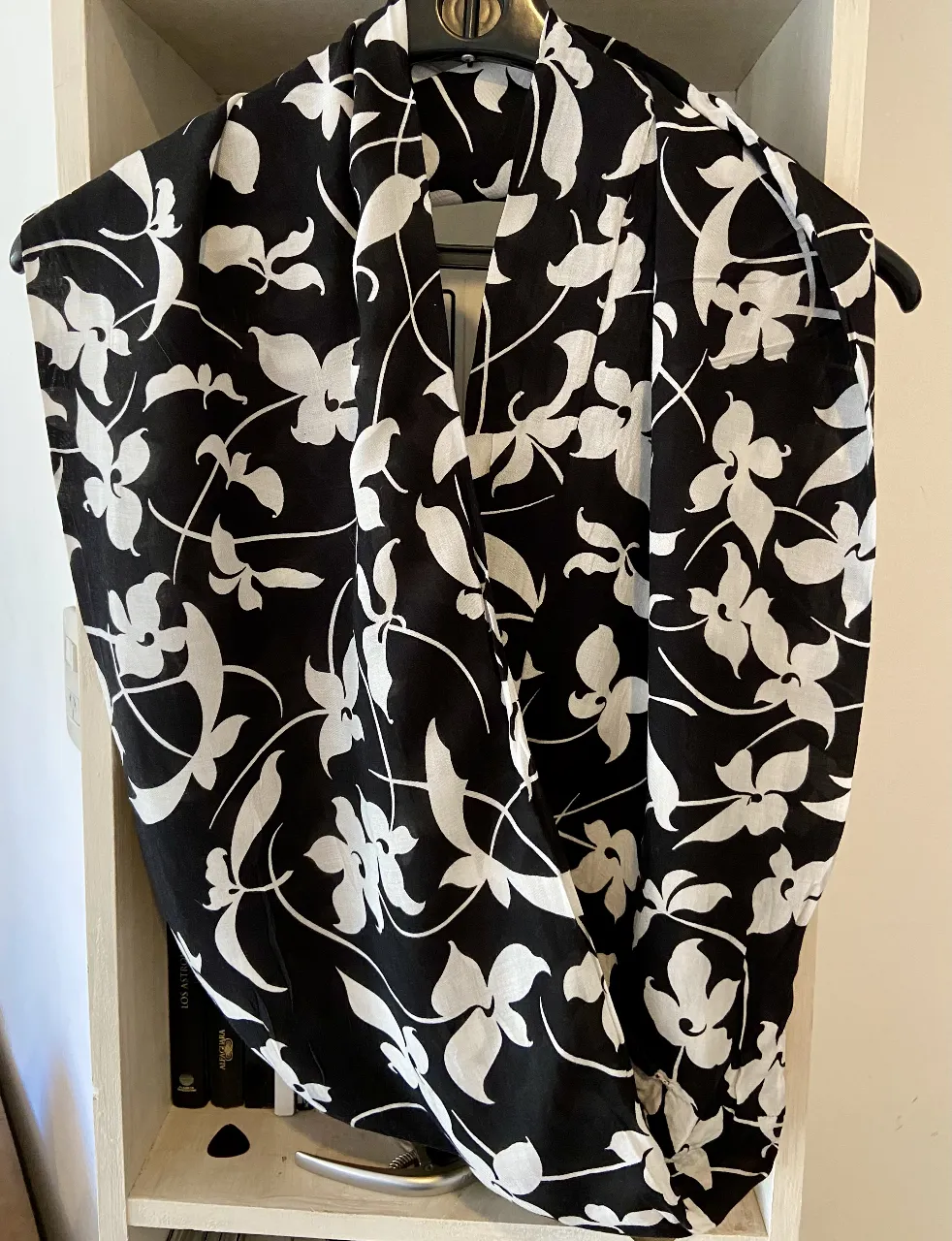 Pañuelo estampado con flores blancas sobre fondo negro. Ideal para complementar cualquier look y darle un toque de estilo.