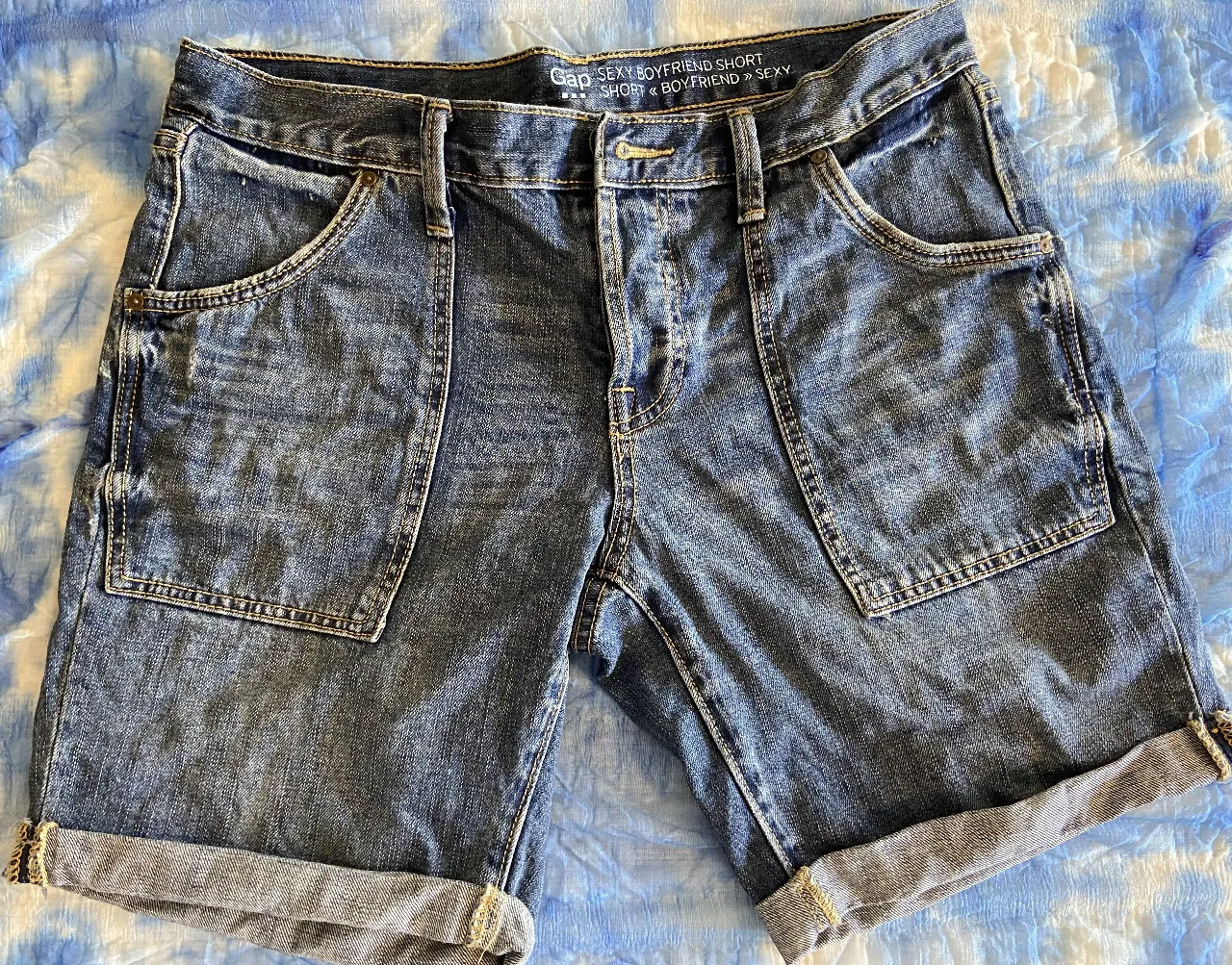 Shorts de jean tiro alto, estilo boyfriend, con bolsillos cargo y dobladillo en el ruedo. Un clásico versátil para tu día a día.