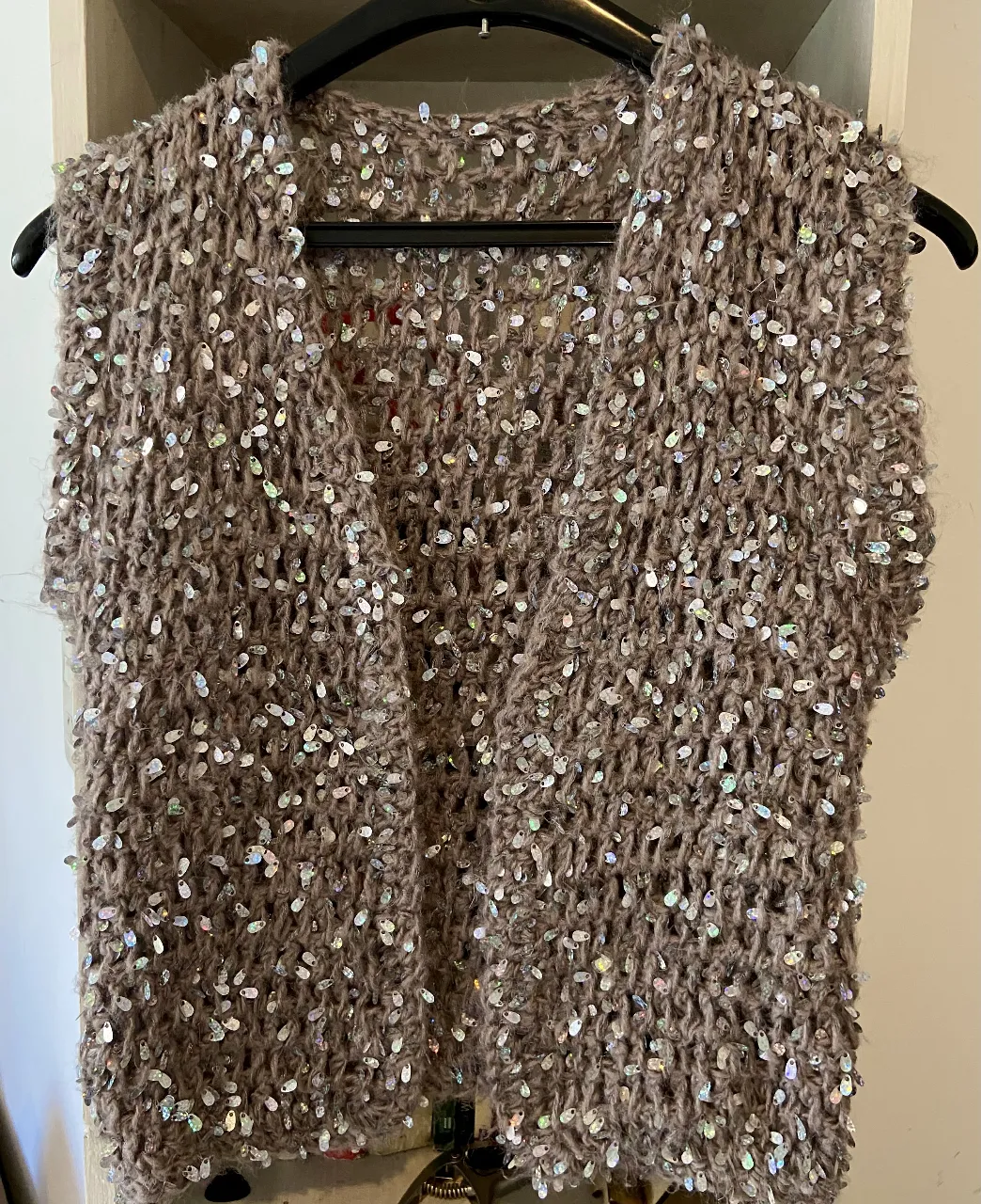 Chaleco tejido con lentejuelas plateadas, ideal para darle un toque de brillo a tu outfit. Perfecto para usar sobre remeras o vestidos.