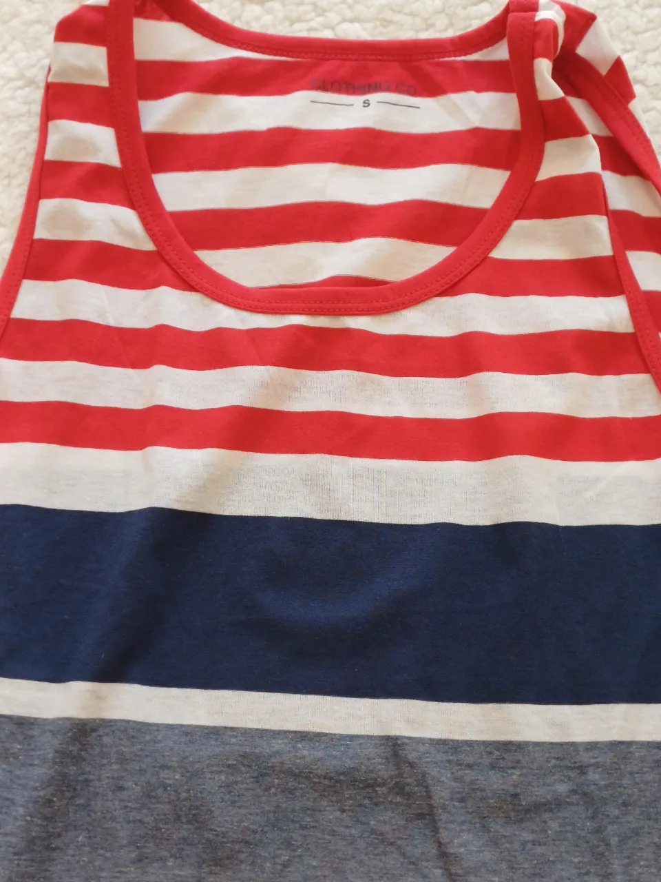 Musculosa a rayas rojas, blancas y azules. Presenta un diseño de franjas horizontales de distintos grosores y colores.