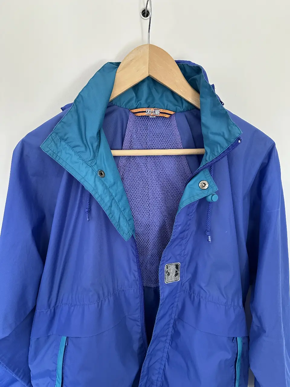 Campera rompevientos vintage azul y verde, ideal para actividades al aire libre. Con capucha y bolsillos, perfecta para protegerte del viento y la lluvia.