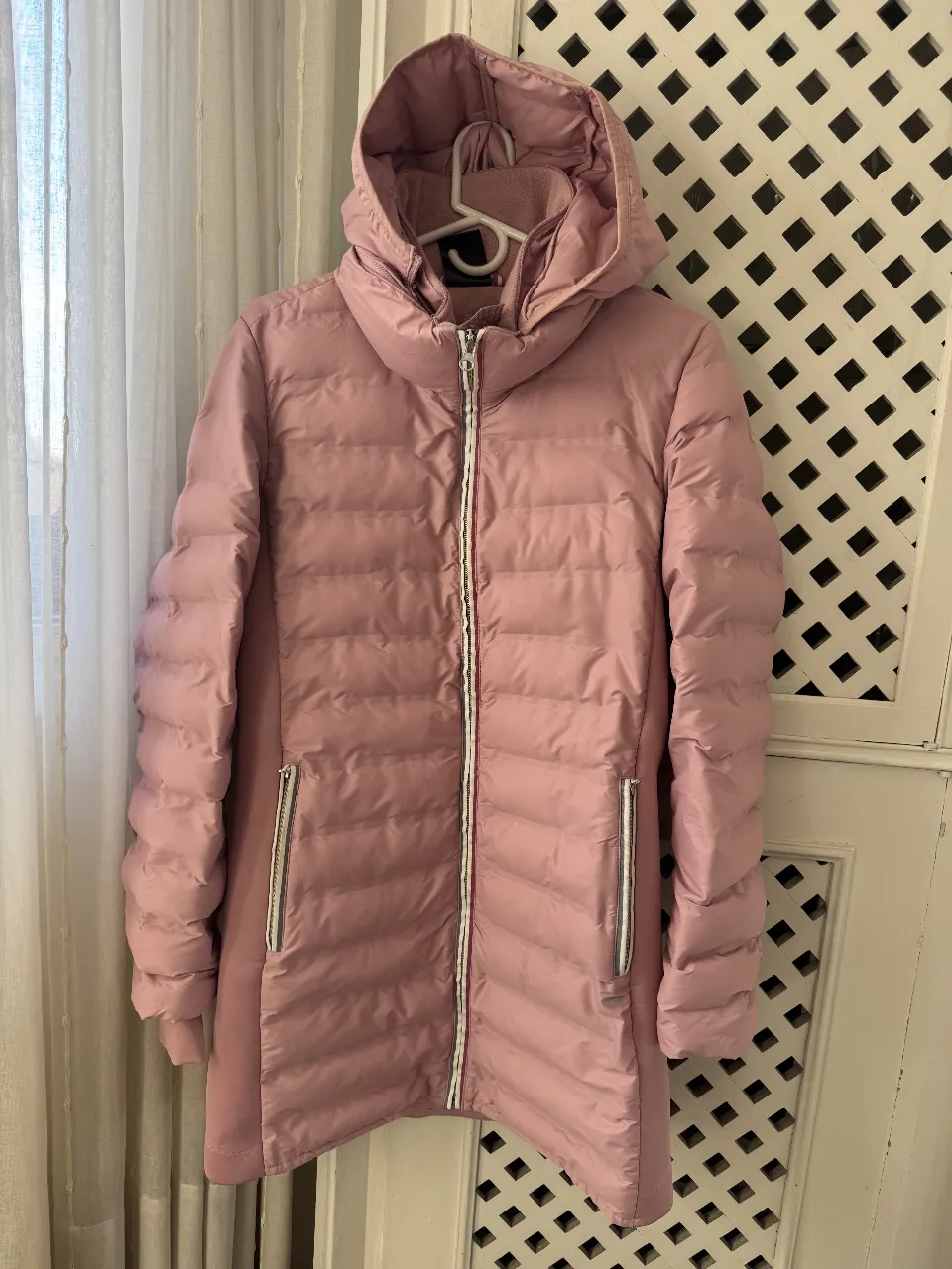 Campera de pluma rosa con capucha y cierre. Ideal para el invierno, cómoda y abrigada. Cuenta con bolsillos con cierre y un diseño moderno.