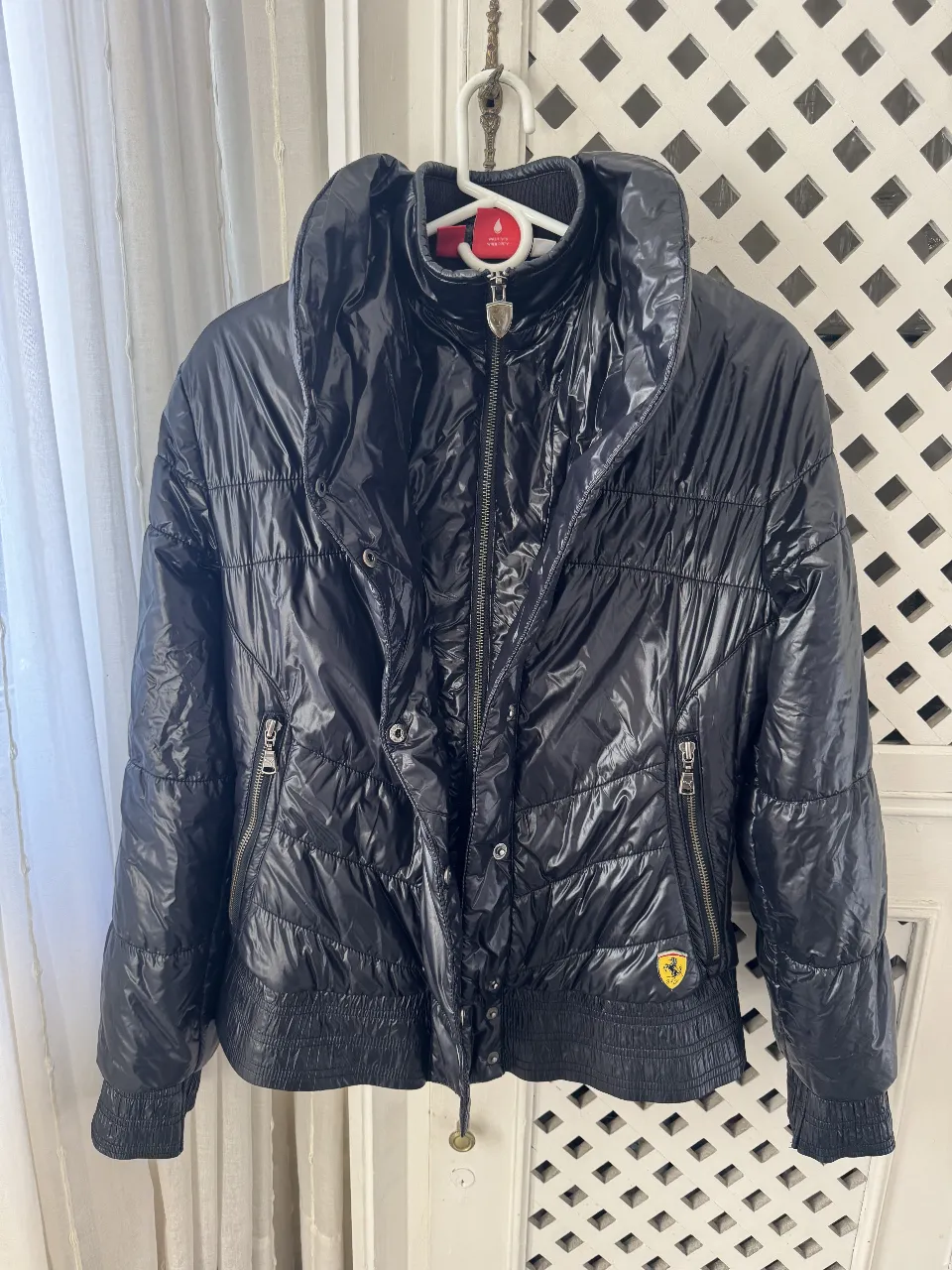 Campera negra acolchada con cuello alto y cierre frontal. Posee detalles de la marca Ferrari en el pecho. Ideal para el invierno.