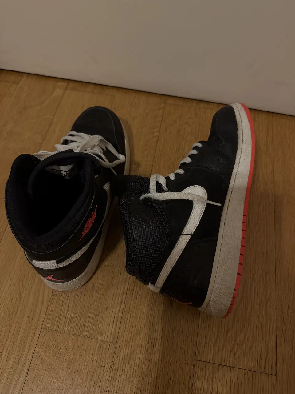 Zapatillas Air Jordan 1 Mid negras con detalles en blanco y rojo/rosita. Talle 8.5Y US. Ideales para un look urbano y deportivo.